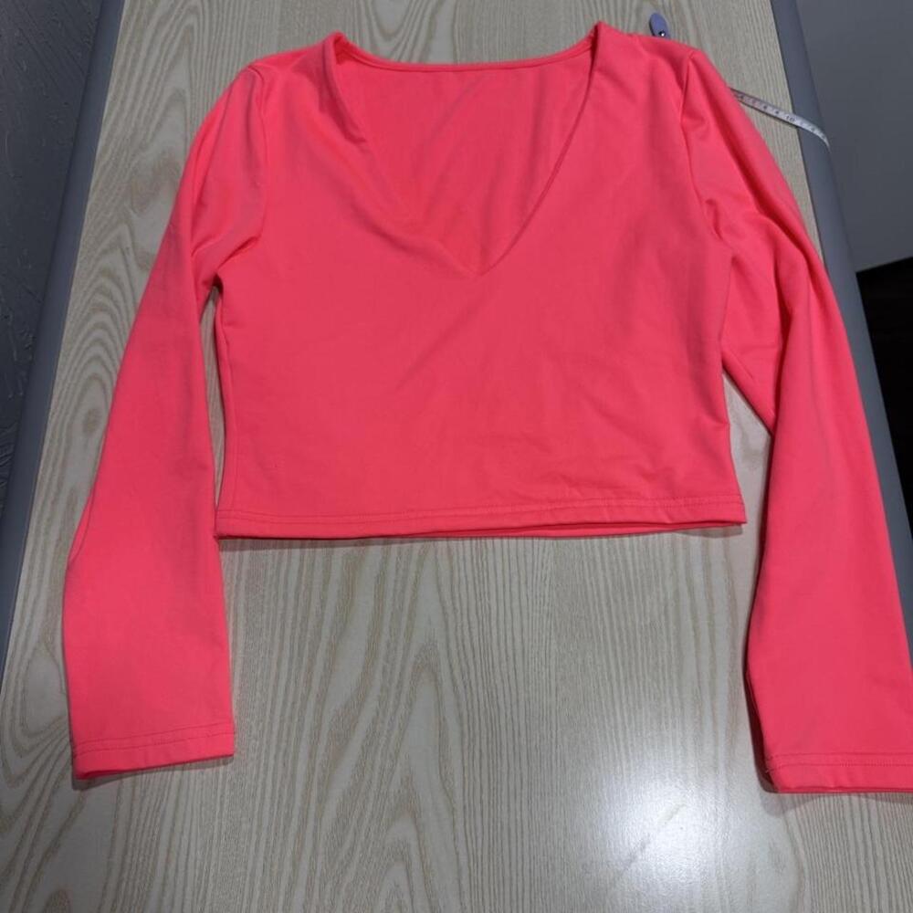 Bright neon coral/pink cropped long-sleeve V-neck top in a soft